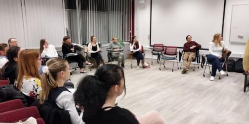 Skupina ljudi sedi v krogu na sestanku v konferenčni sobi.